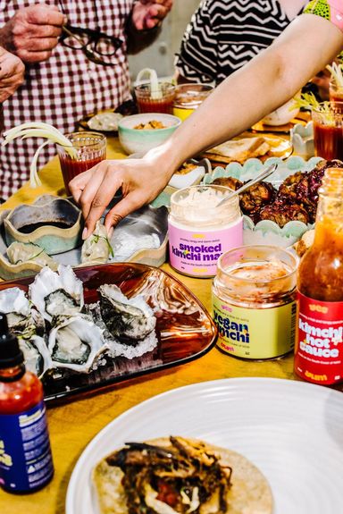 A table set with a feast and a jar of Yes Yum Smoked Kimchi Mayo